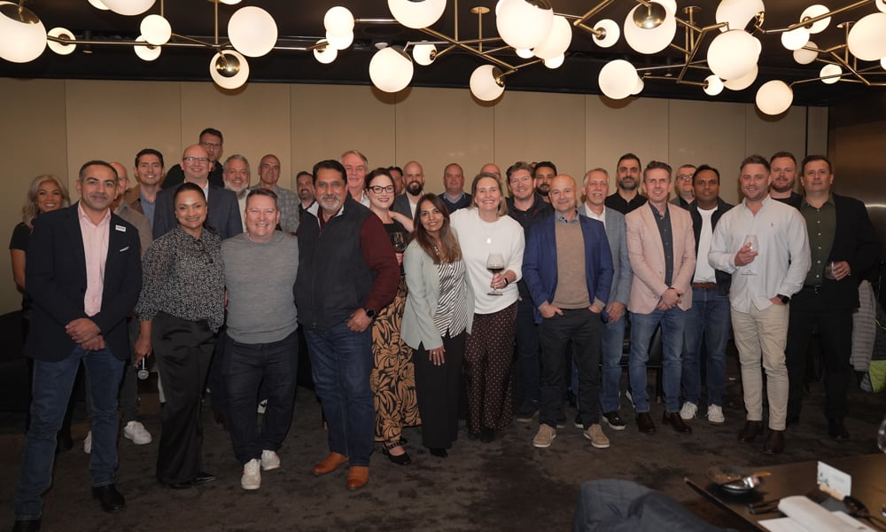 Large group of people posing together indoors under modern globe pendant lights.