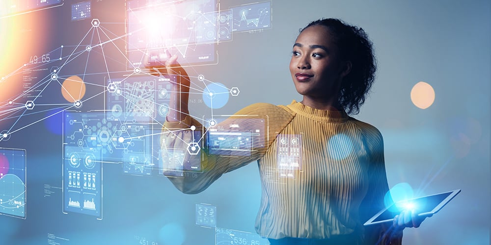Person interacting with holographic data dashboards while holding a tablet.