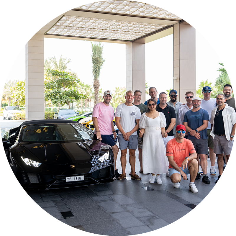 Team standing next to luxury car