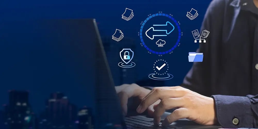 Hands typing on a laptop with digital icons representing data transfer, cloud storage, security, and file management overlayed on a dark blue background.