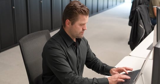 Person working on a laptop at a desk in an office.
