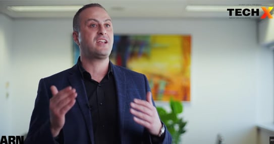 Person speaking to camera indoors, gesturing with their hands.