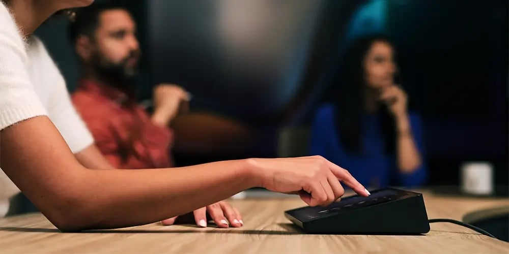 Person tapping a touchscreen meeting room control panel.