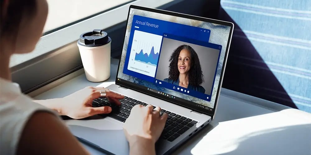 Person working on a laptop showing a video call and revenue charts.