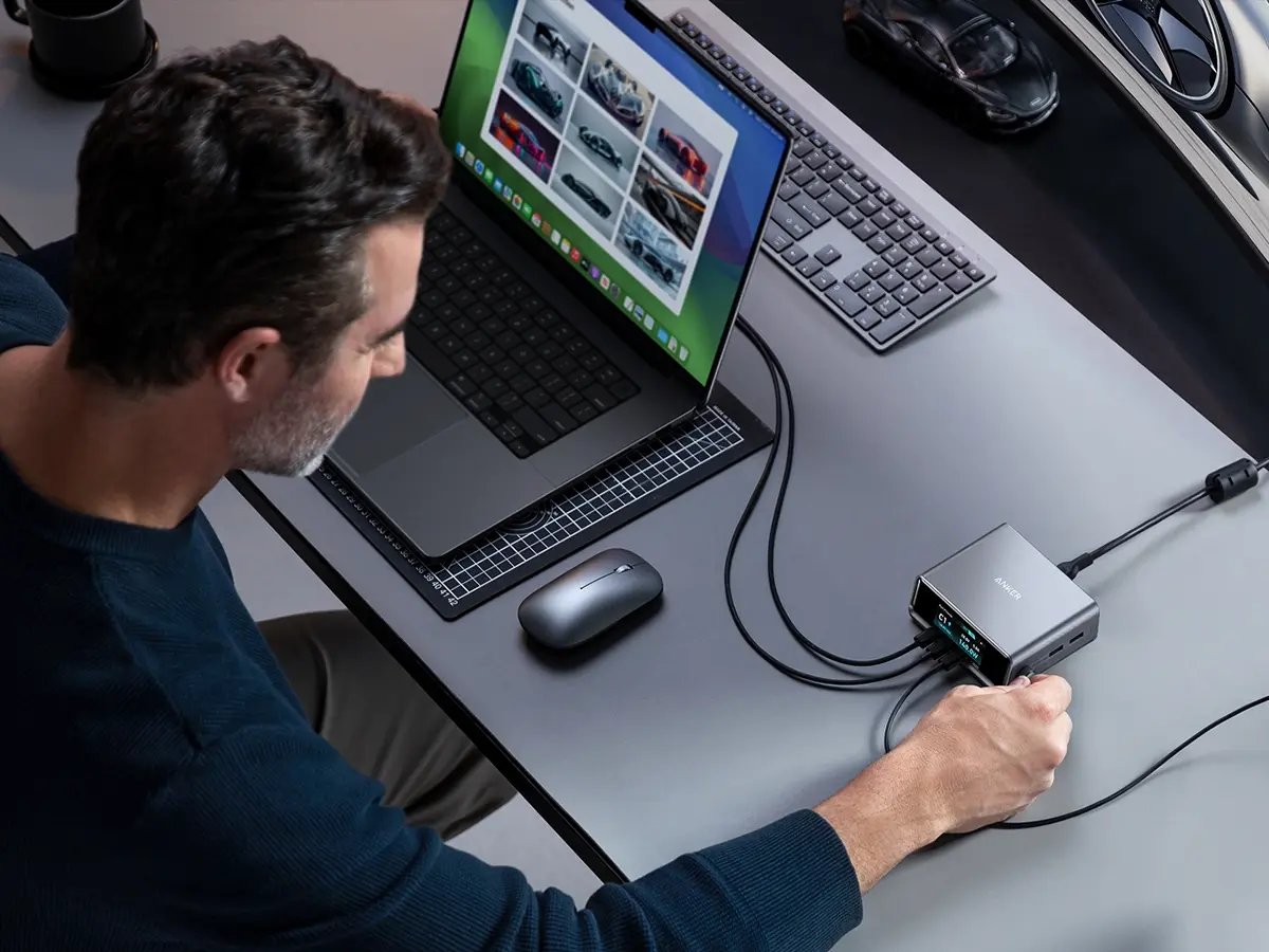 Person connecting a laptop to a docking station on a desk.
