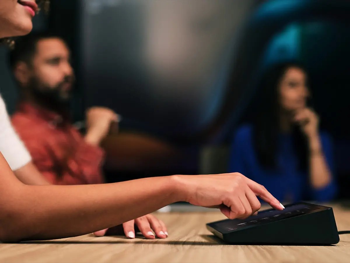Person tapping a touchscreen meeting room control panel.