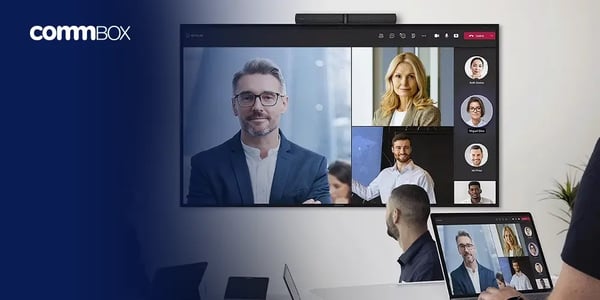 Large display showing a video conference interface with multiple participants, and a person using a laptop in front.
