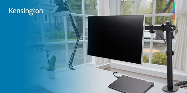 Minimalist desk setup with a monitor mounted on an adjustable arm and a laptop below.