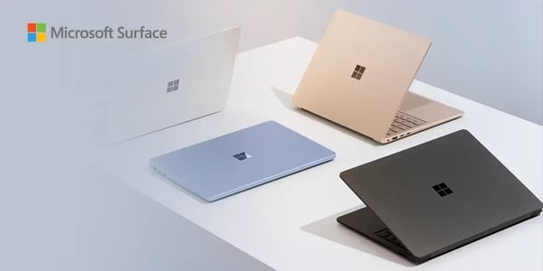 Four Microsoft Surface laptops in different colors arranged on a white surface.