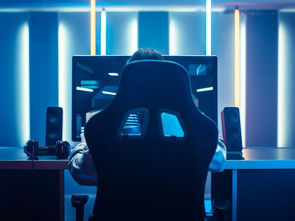 Person seated at a desktop workstation with neon lighting.