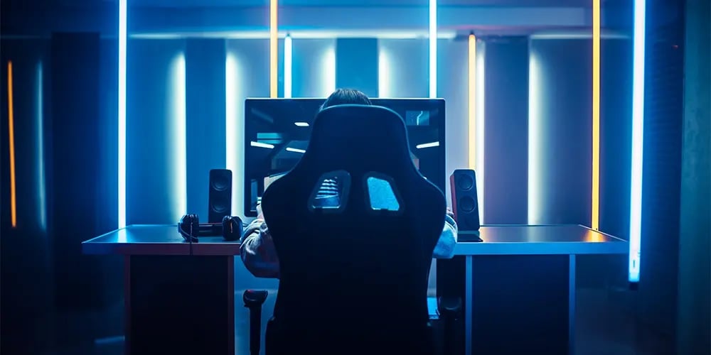 Person seated at a desktop workstation with neon lighting.