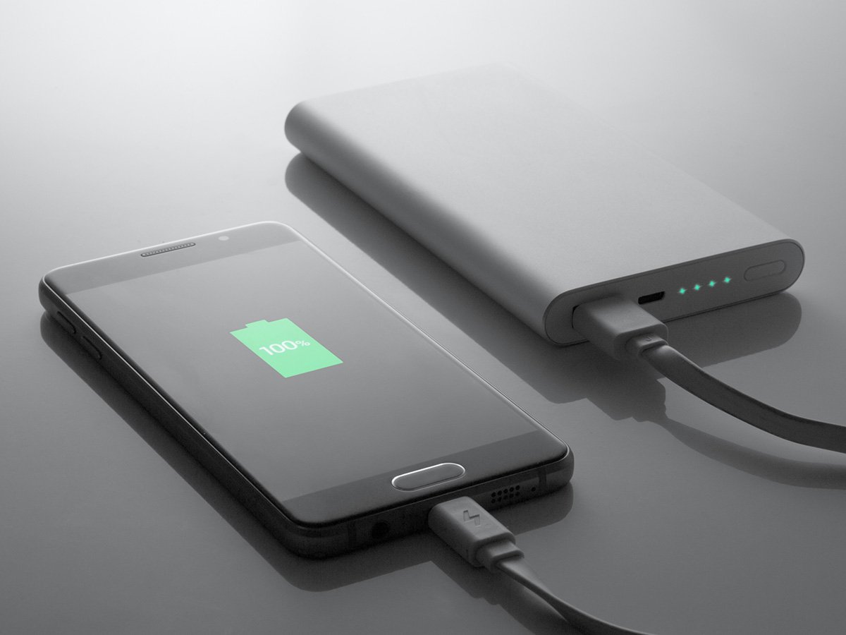 Smartphone connected to a power bank showing a full battery icon.