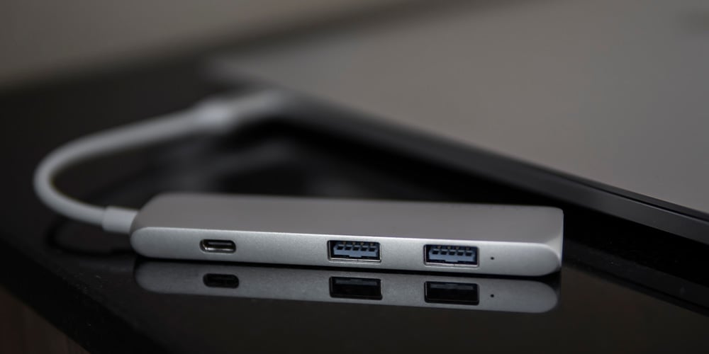 USB‑C hub with USB ports and a cable resting on a desk.