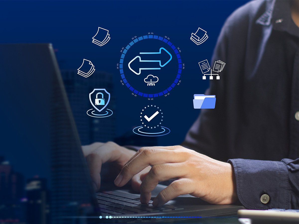 Hands typing on laptop with digital icons for file transfer and security.