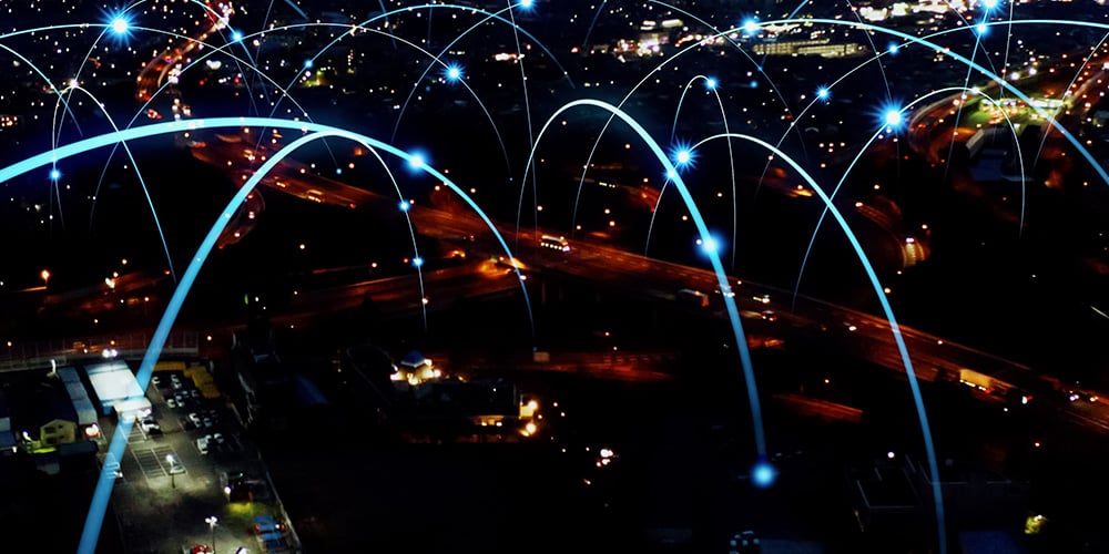 Night cityscape with digital arcs connecting locations, representing wide‑area network connectivity.