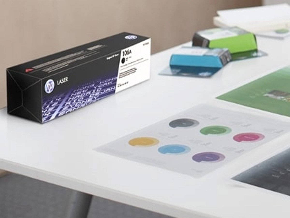 HP Laser toner cartridge box on a desk with color charts and papers.