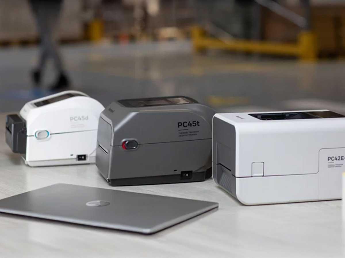 Three Honeywell desktop label printers placed on a table with a laptop.