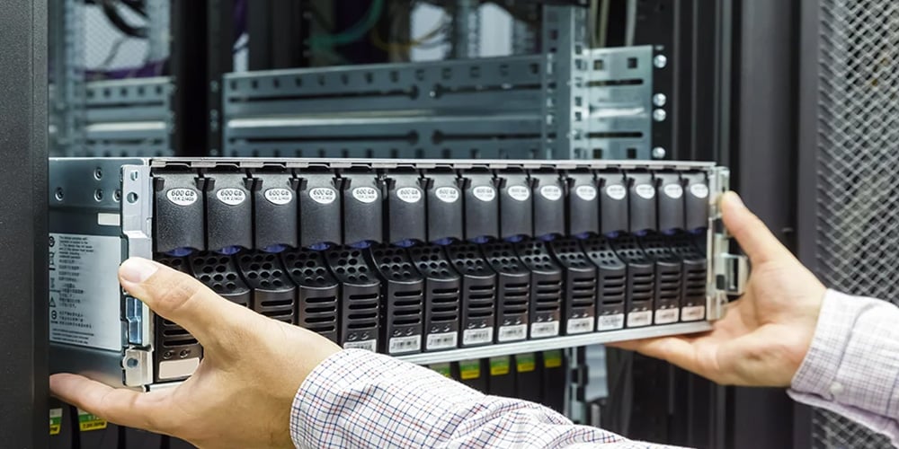 Hands installing a server component into a rack in a data center.