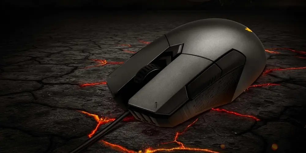 Black wired gaming mouse resting on a cracked, lava‑like surface with glowing orange lines.