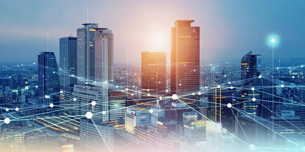 Futuristic cityscape at dusk with illuminated skyscrapers, digital interconnected lines, and glowing nodes conveying connectivity and advanced technology.