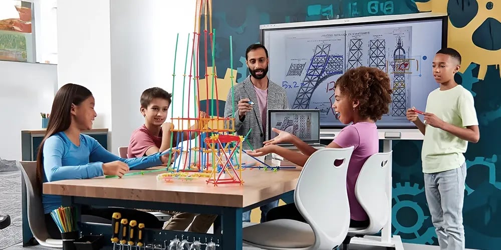 Students and a teacher engage in a STEM class. They build a colorful tower with connectors. A screen shows technical drawings. Mood: collaborative, educational.