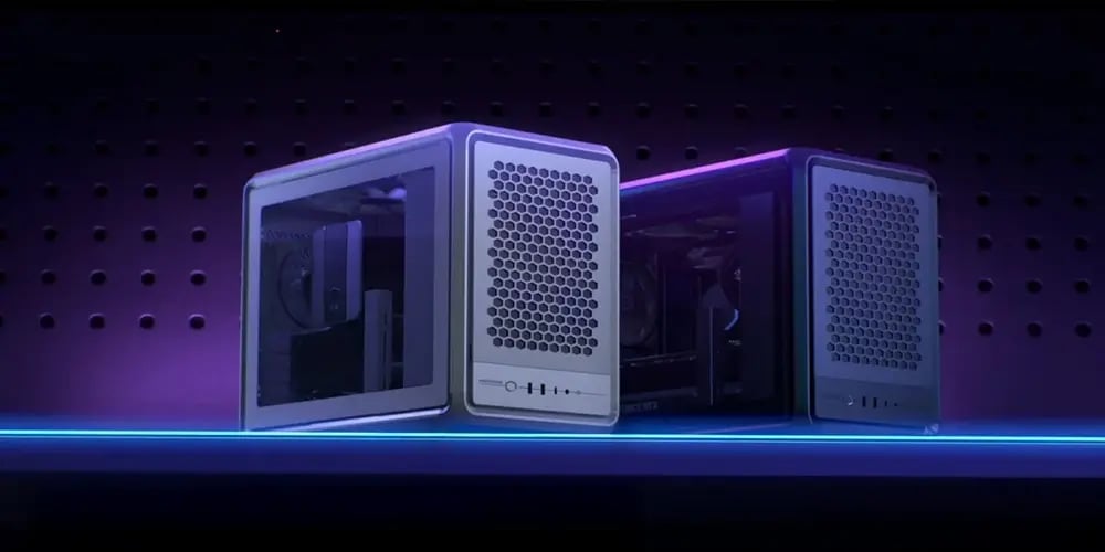 Two sleek, cube-shaped computer cases with mesh fronts are displayed against a dark, perforated backdrop. A glowing blue line adds a modern, futuristic feel.