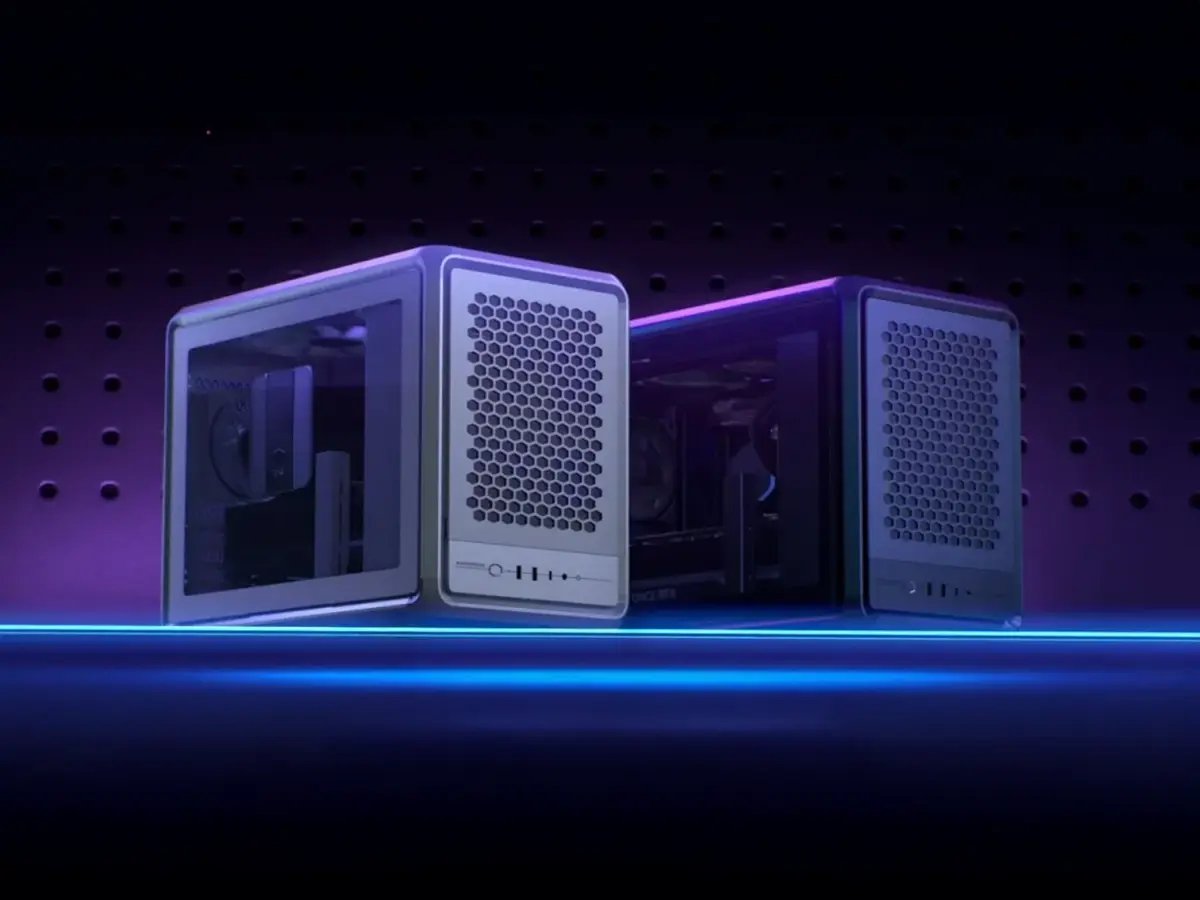 Two sleek, cube-shaped computer cases with mesh fronts are displayed against a dark, perforated backdrop. A glowing blue line adds a modern, futuristic feel.
