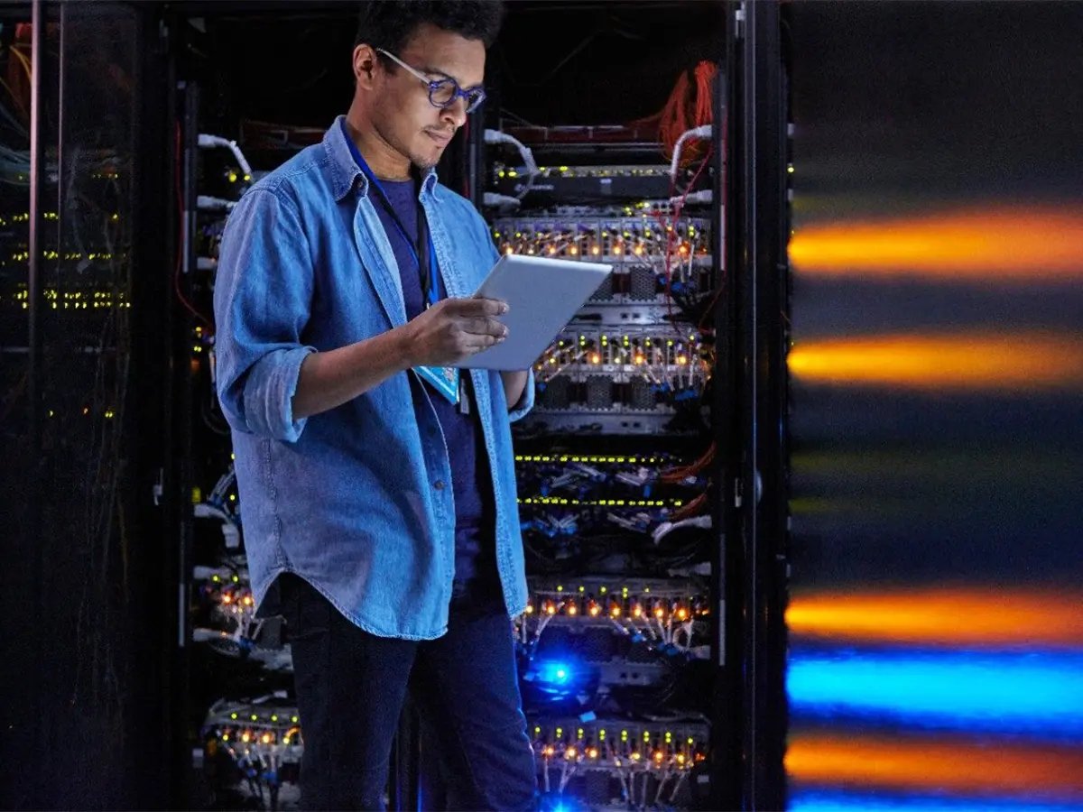 Person using a tablet in front of Eaton server racks with illuminated network equipment.