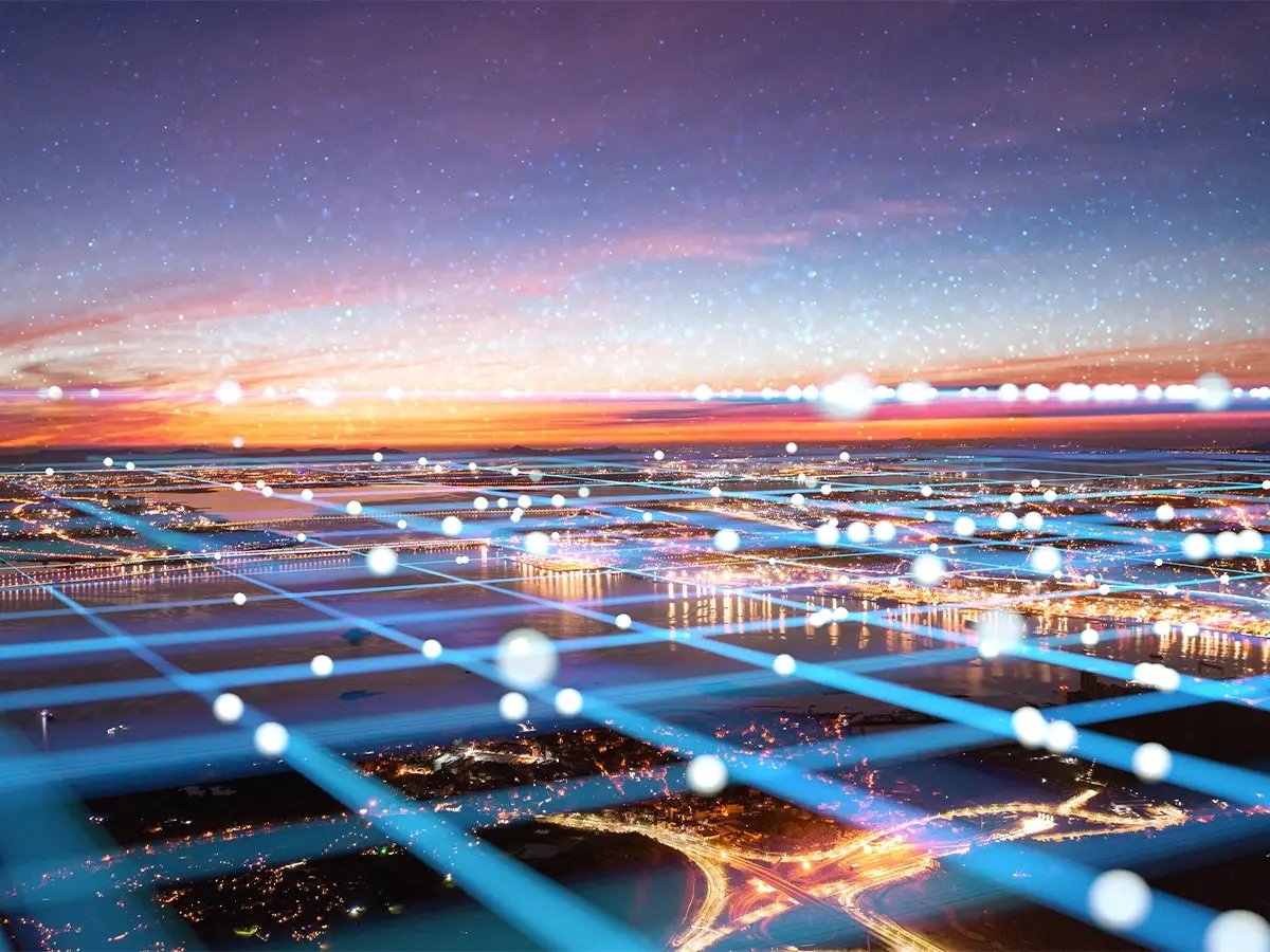 Cityscape at sunset with glowing blue grid lines and light points representing Eaton network connectivity.