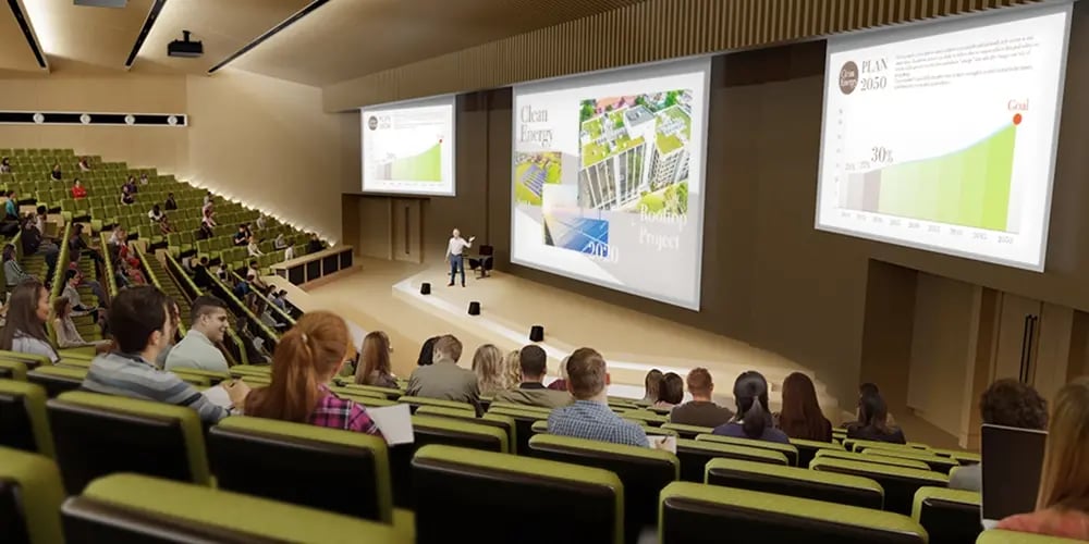 Lecture hall with tiered seating where a presenter is giving a presentation on clean energy, displayed on large screens showing charts and images.
