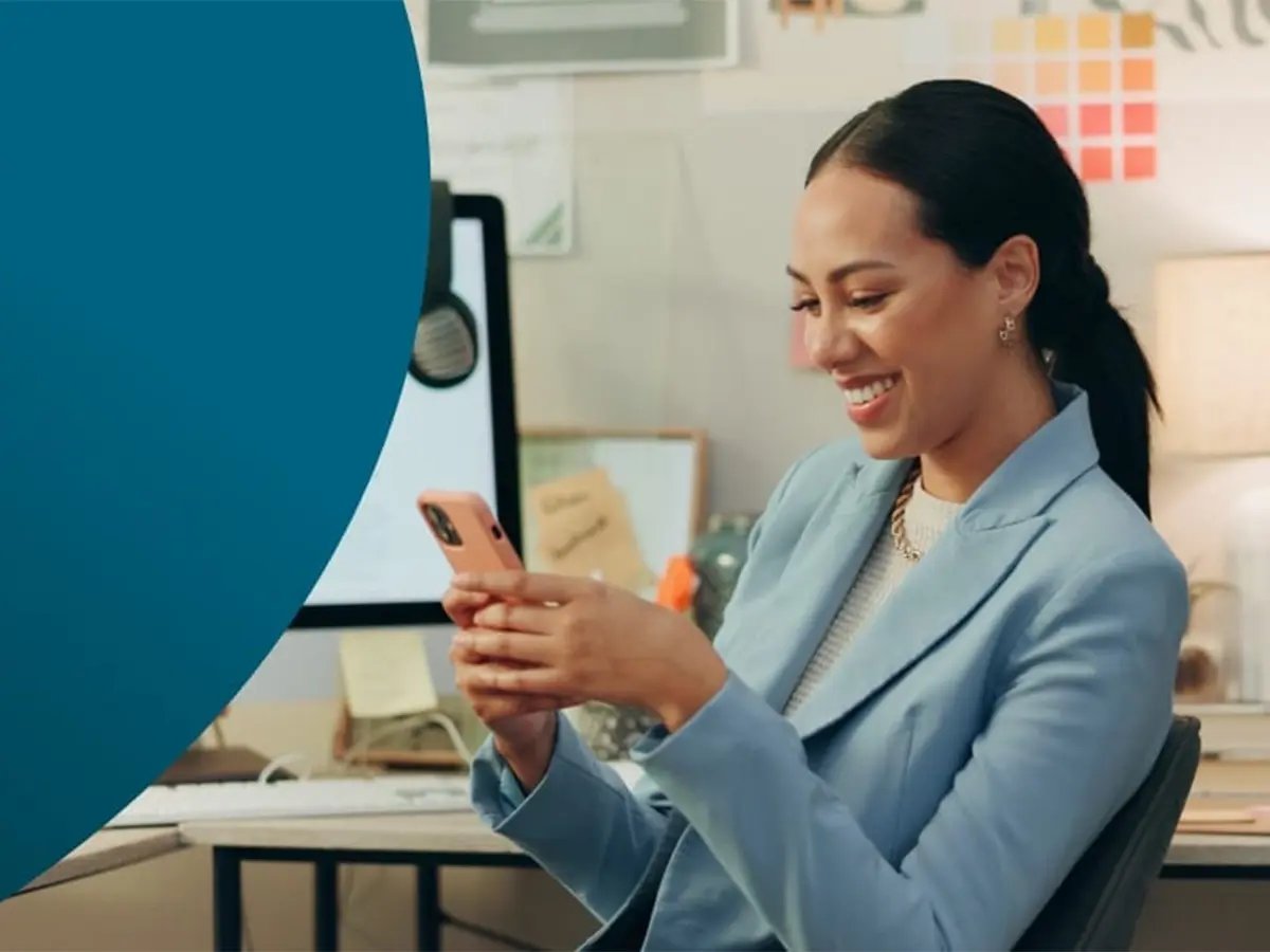 Person in a blue blazer holding a smartphone, representing mobile voice recording in a modern workspace.