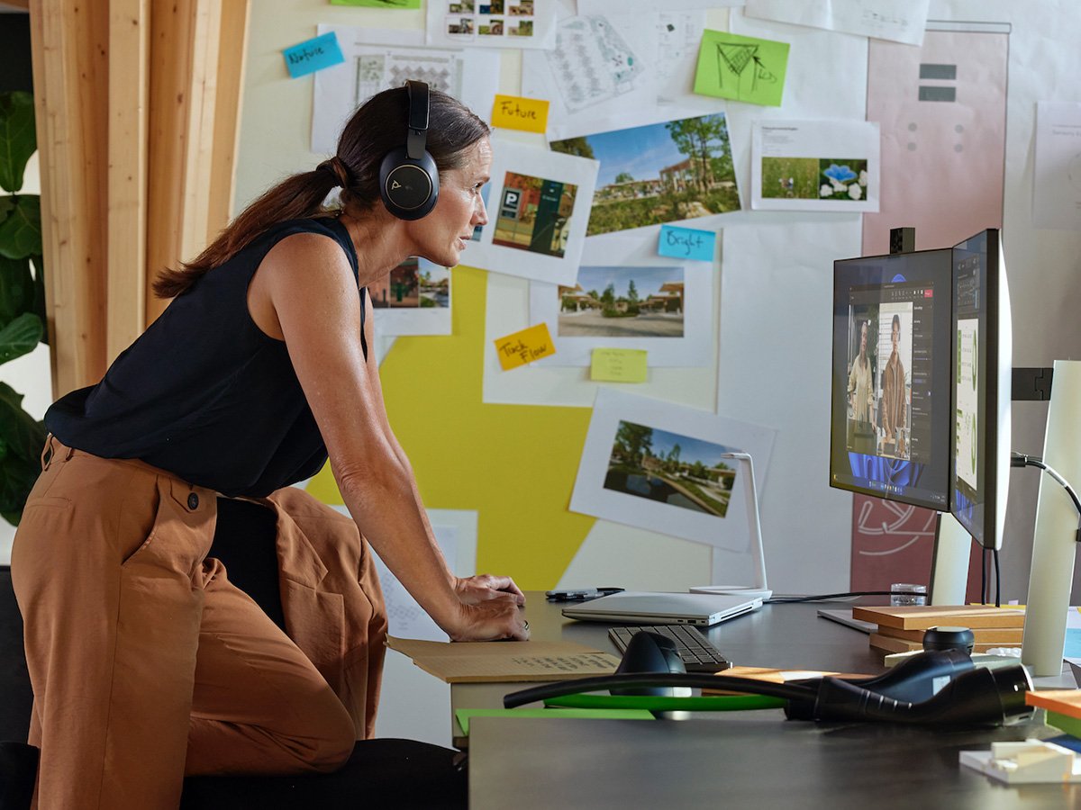 A person wearing headphones at their office desk, working at their HP desktop computer