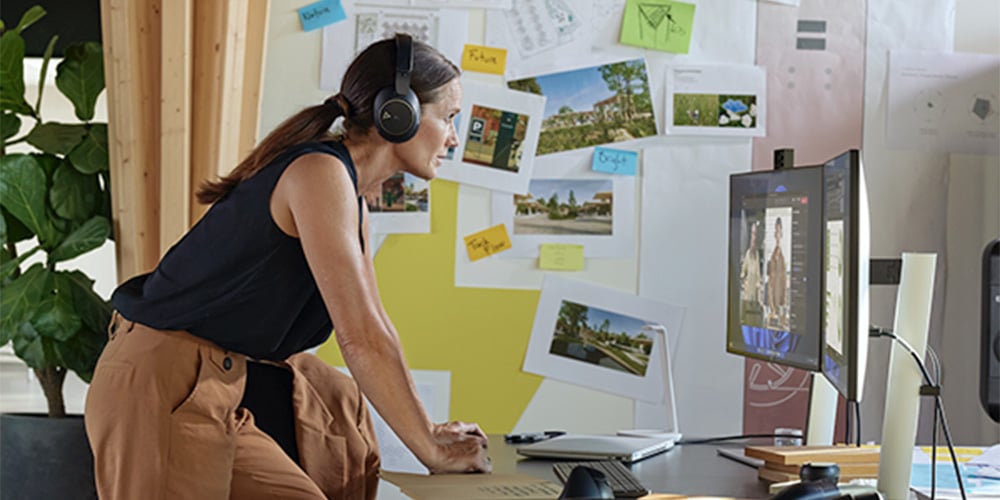 A person wearing headphones at their office desk, working at their HP desktop computer