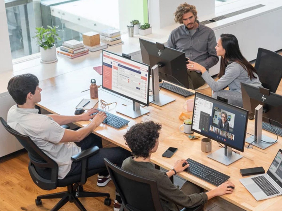 An open plan office setting with 4 people sitting at their HP computer stations