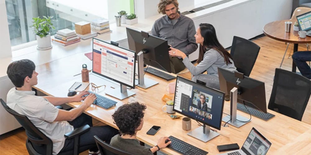 An open plan office setting with 4 people sitting at their HP computer stations