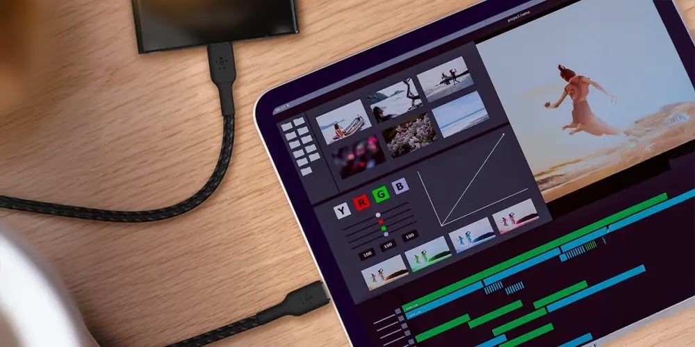 A tablet displaying a video editing interface, connected with braided cables.