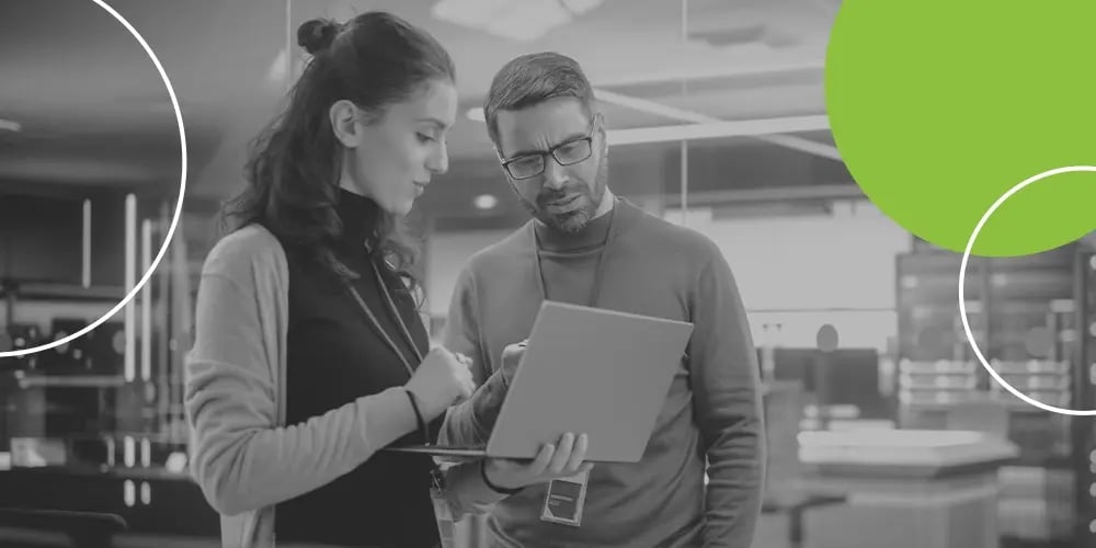 Two colleagues reviewing information on a laptop in a modern office.