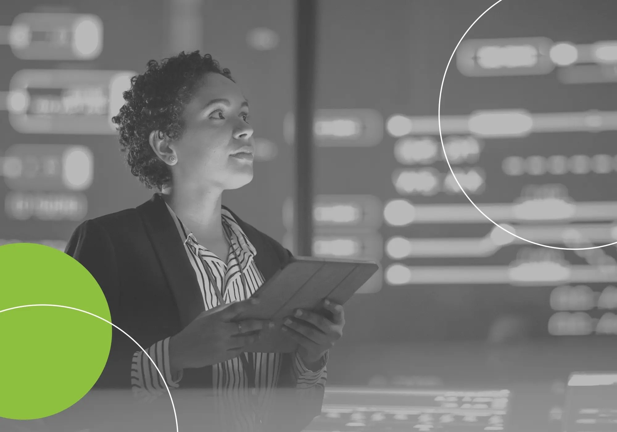 Individual holding a tablet while standing in front of a large digital display.