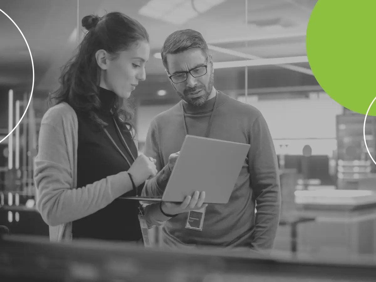 Two colleagues reviewing information on a laptop in a modern office.