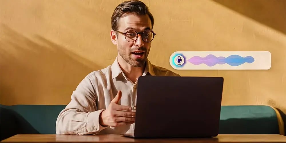 Person speaking to a laptop with a voice assistant interface on screen.