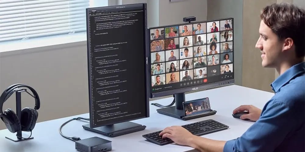 Person working at a desk with dual monitors showing code and a video call.