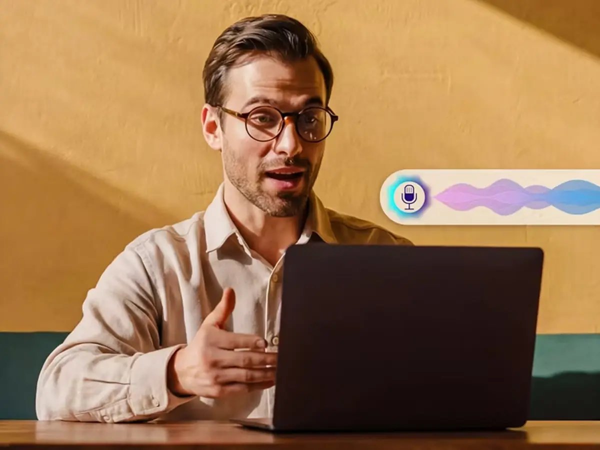 Person speaking to a laptop with a voice assistant interface on screen.