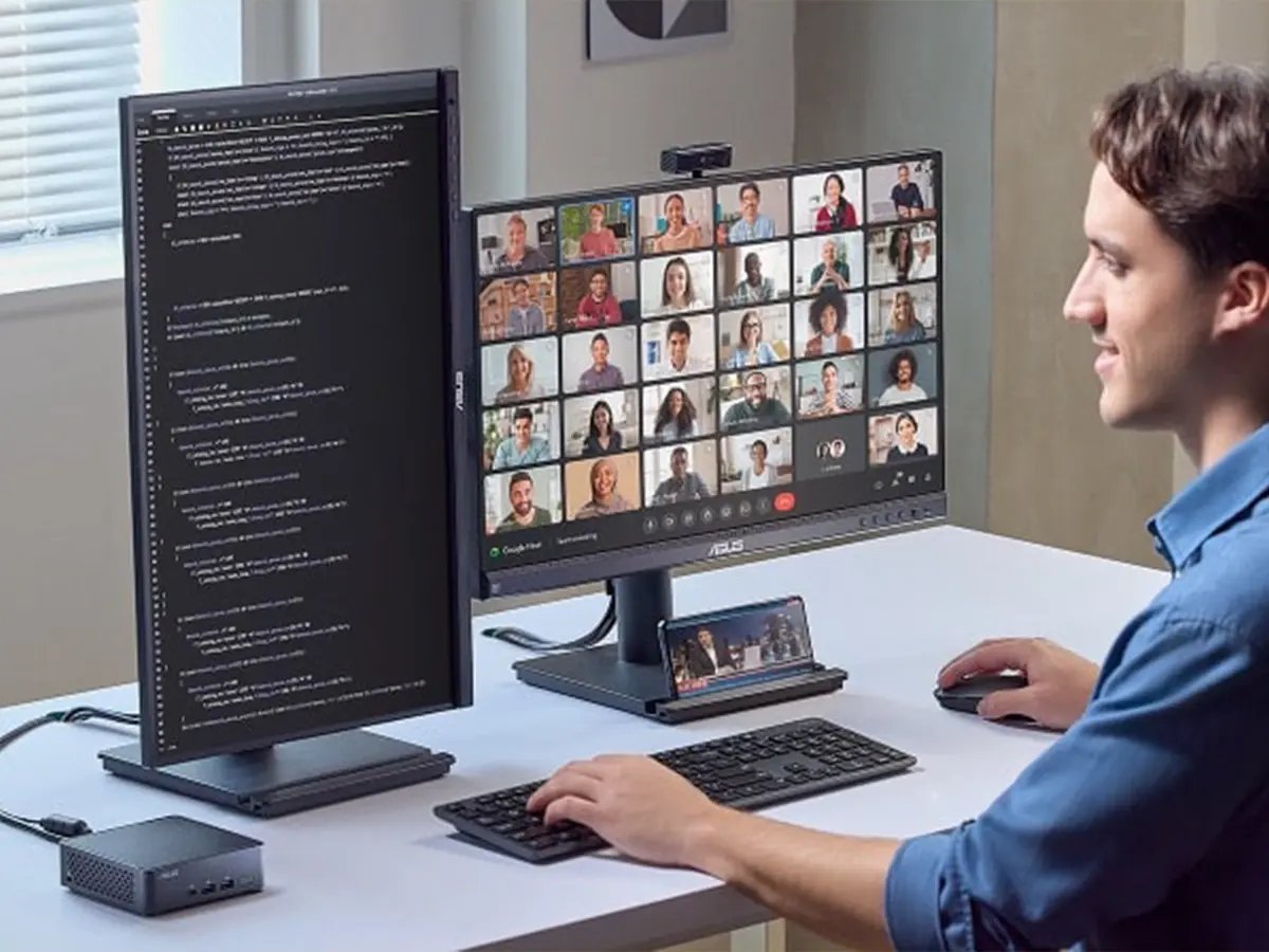 Person working at a desk with dual monitors showing code and a video call.