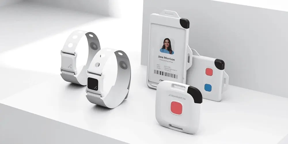 Wearable bands and badge-style IoT devices arranged on a white surface.