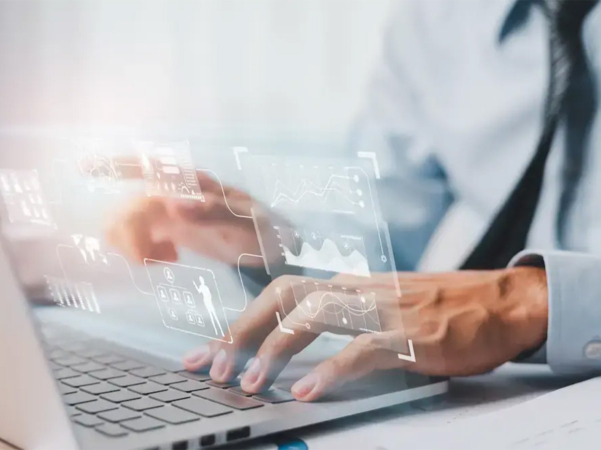 Hands typing on a laptop with transparent data charts and user interface elements overlaid.