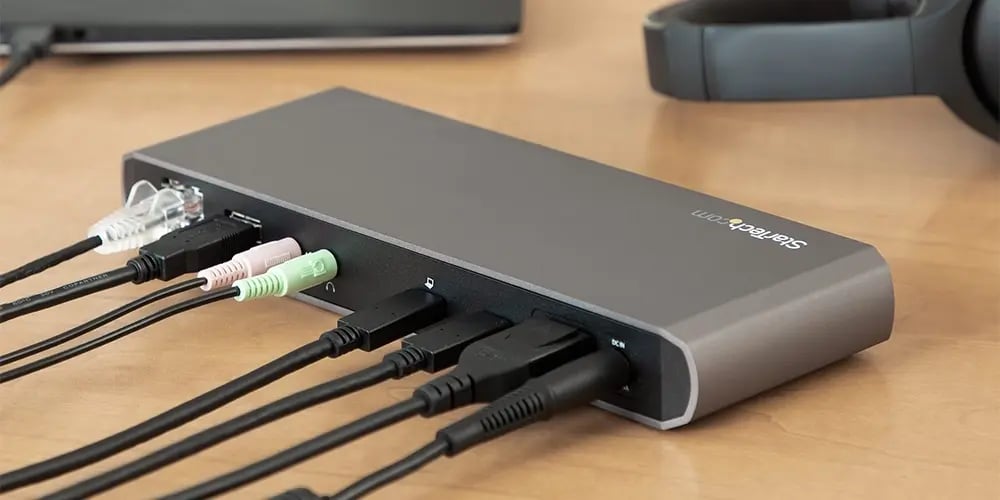 A StarTech docking station on a desk with multiple audio, USB, and network cables plugged in.
