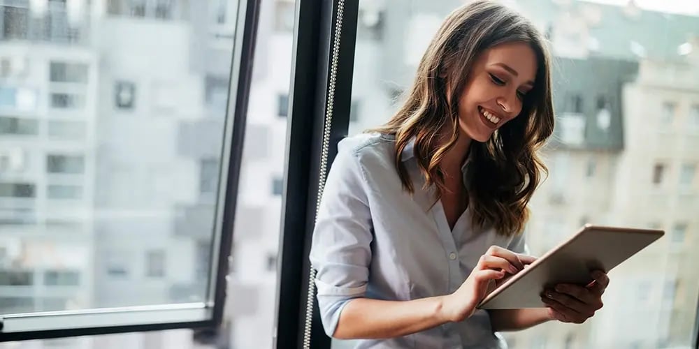 Person standing near a window with city buildings in the background.