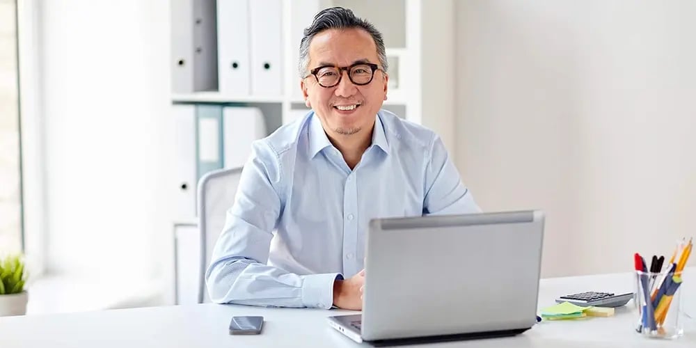 Person sitting at a desk using a laptop in a bright office.
