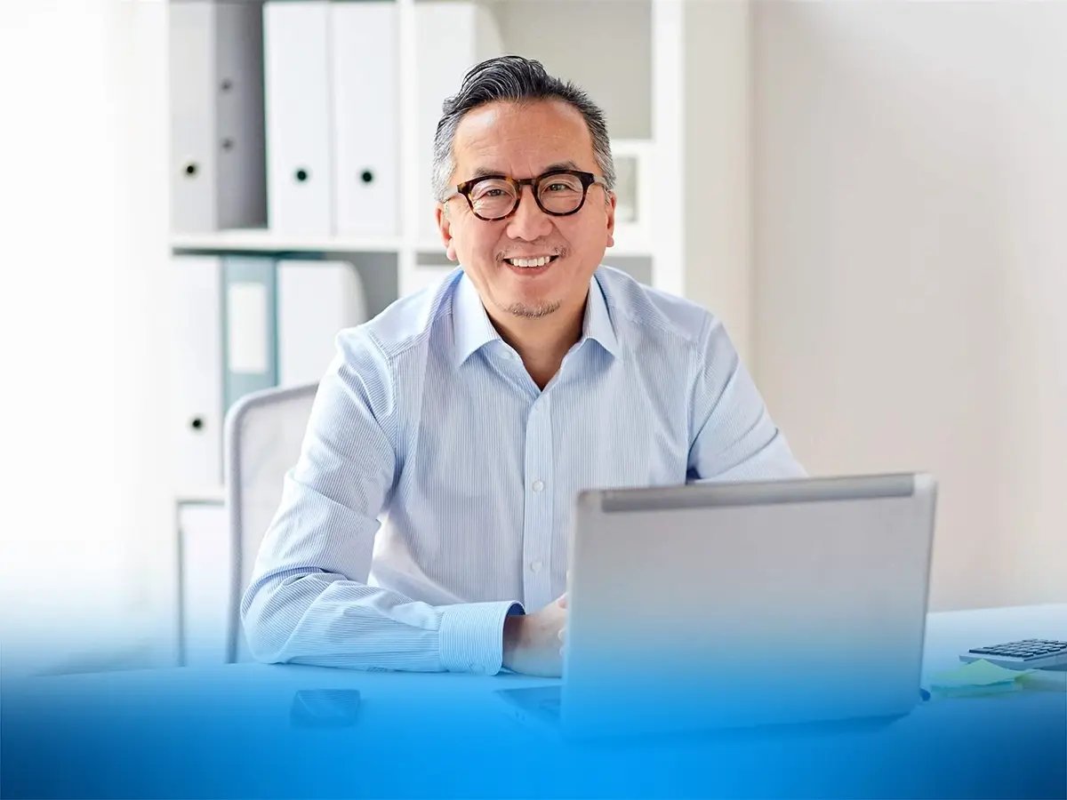 Person sitting at a desk using a laptop in a bright office.
