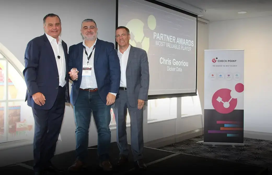 Three people standing together in front of a screen showing “Partner Awards Most Valuable Player” and a banner.